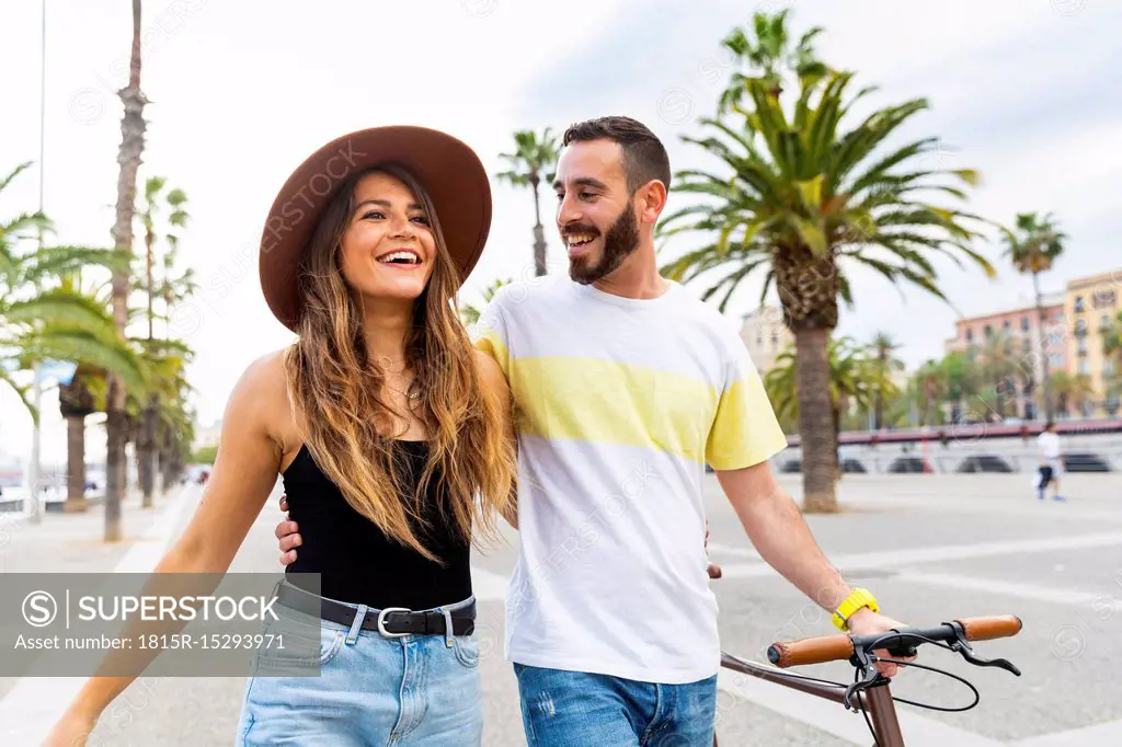 Spain, Barcelona, happy couple walking on seaside promenade