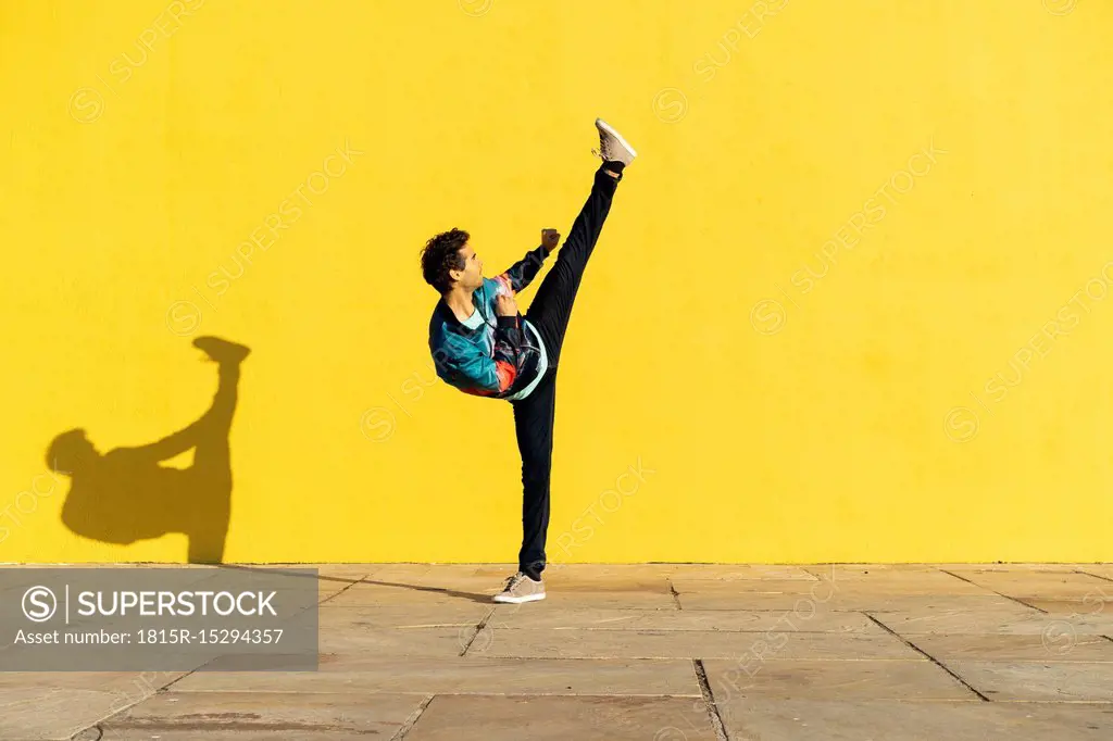 Acrobat doing movement training in front of a yellow wall