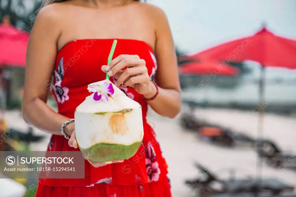 Thailand, woman holding fresh coconut, partial view