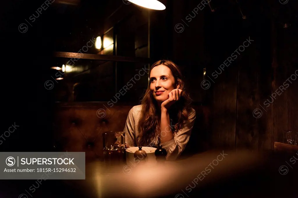 Smiling woman sitting at dining table looking sideways