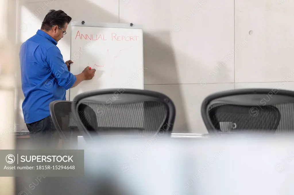 Businessman writing on whiteboard in conference room