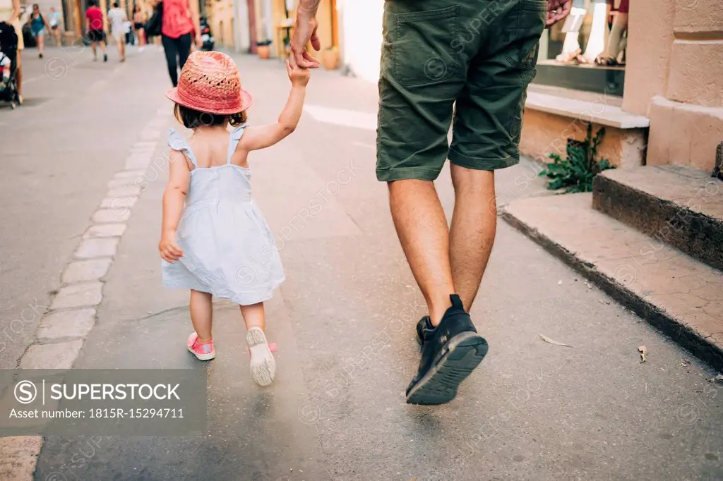 France, Aix-en-Provence, toddler girl and father walking hand in hand in the city