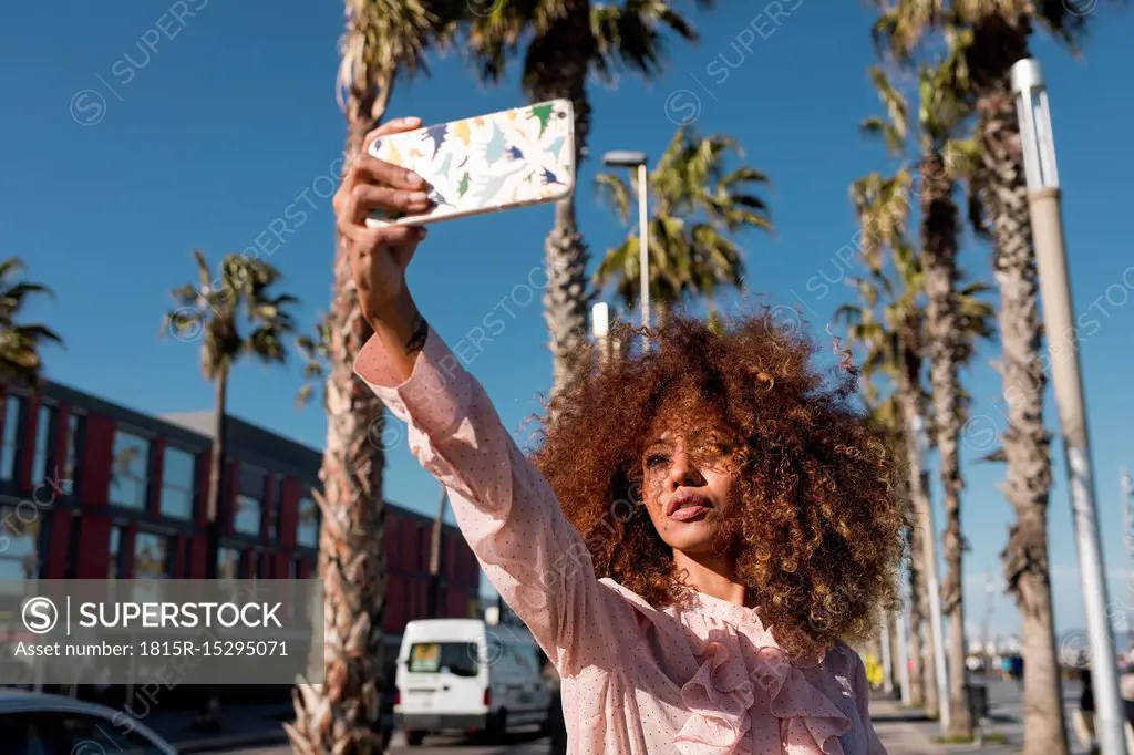 Stylish young woman taking a selfie at seaside promenade