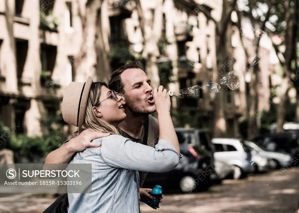 Couple blowing soap bubbles in the city together