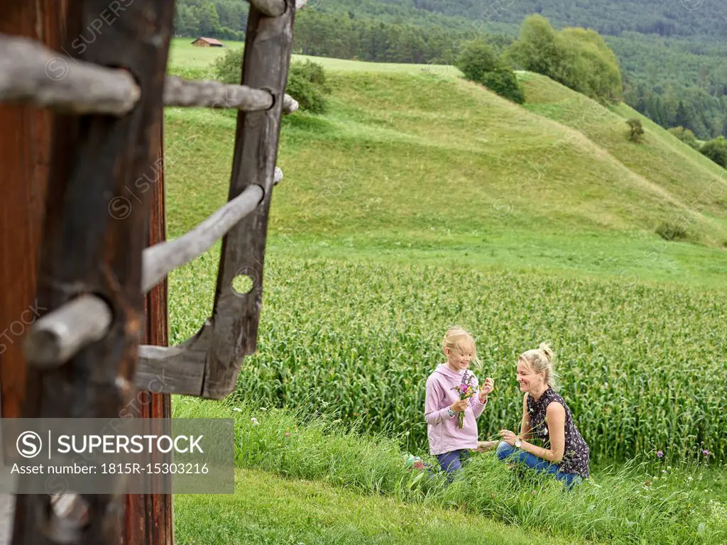 Happy mother and daughter picking flowers in the countryside