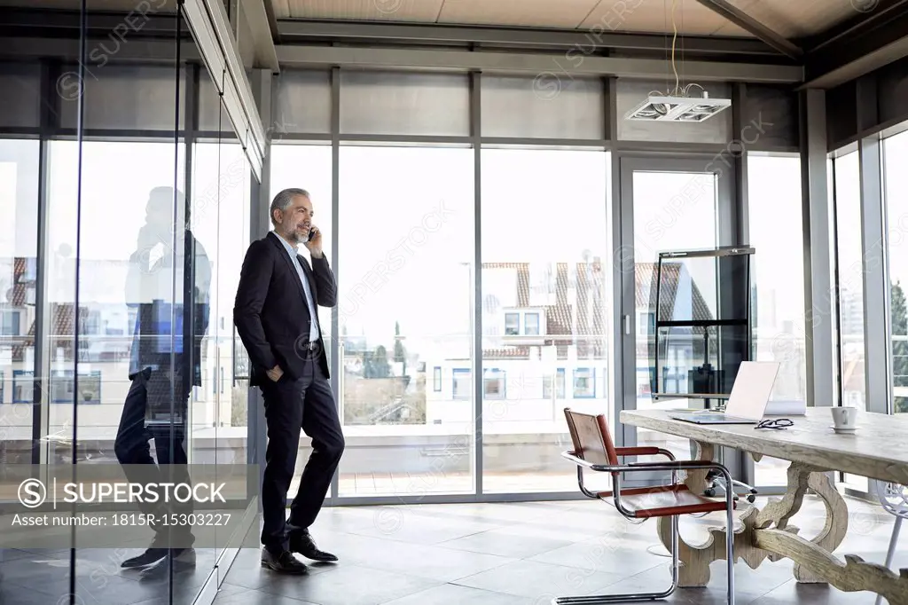 Businessman standing in office talking on cell pohone