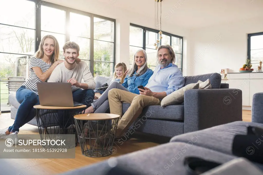 Extended family sitting on couch, using mobile devices