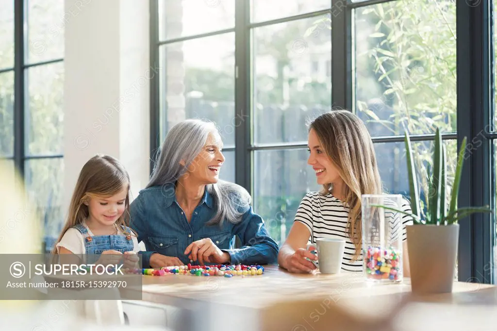 Grandmother and granddaughter and mother threading beads