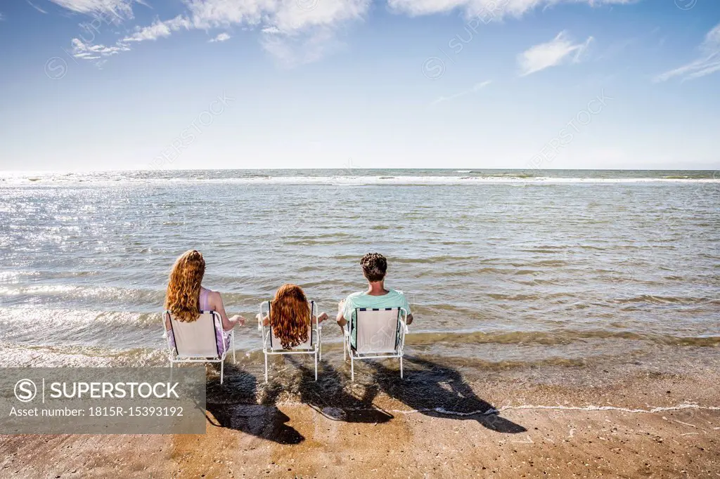 Netherlands, Zandvoort, family sitting on chairs in the sea