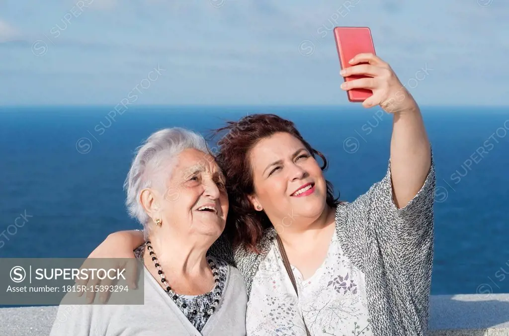 Grandmother and granddaughter taking a selfie in front of the sea