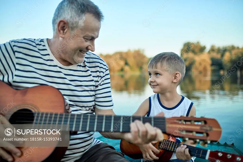 Grandfather teaching grandson playing guitar