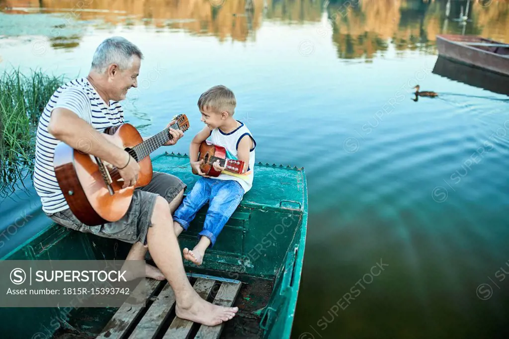 Grandfather teaching grandson playing guitar