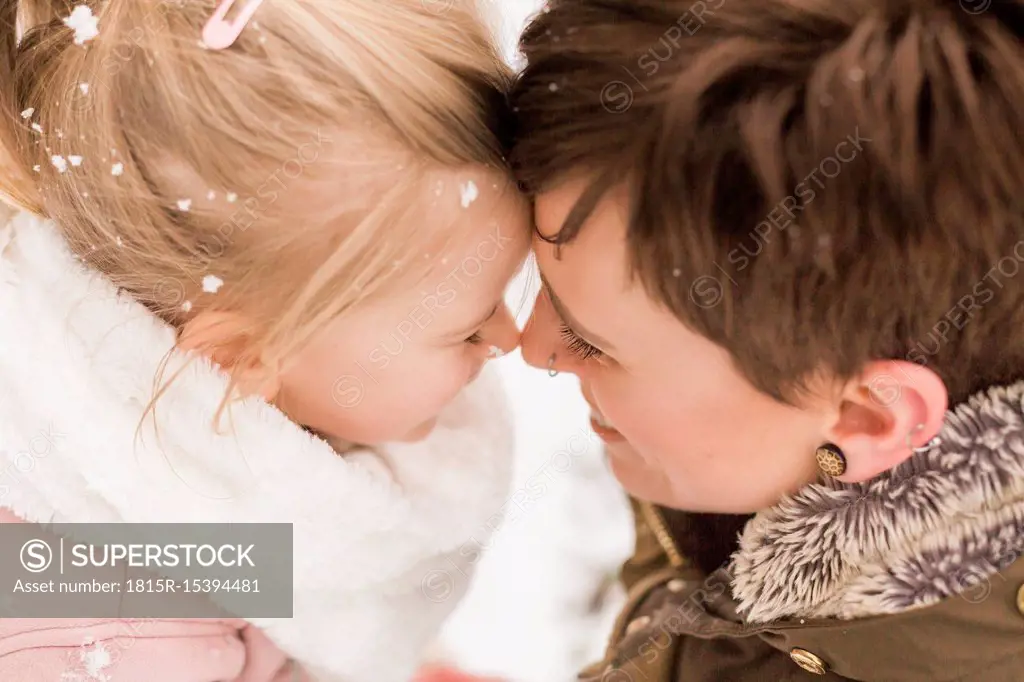 Little girl snuggling with her mother in the snow