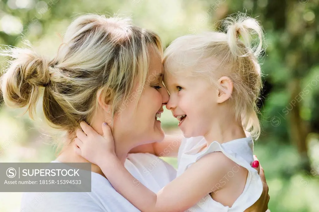 Happy mother cuddling her daughter in nature