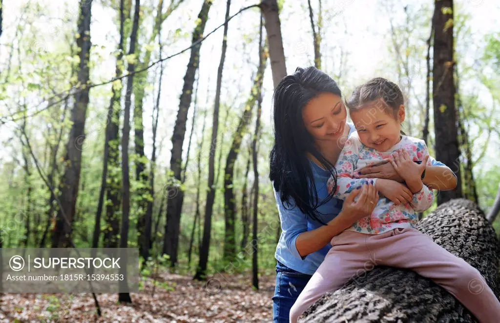 Mother and daughter in park, sitting on tree trunk