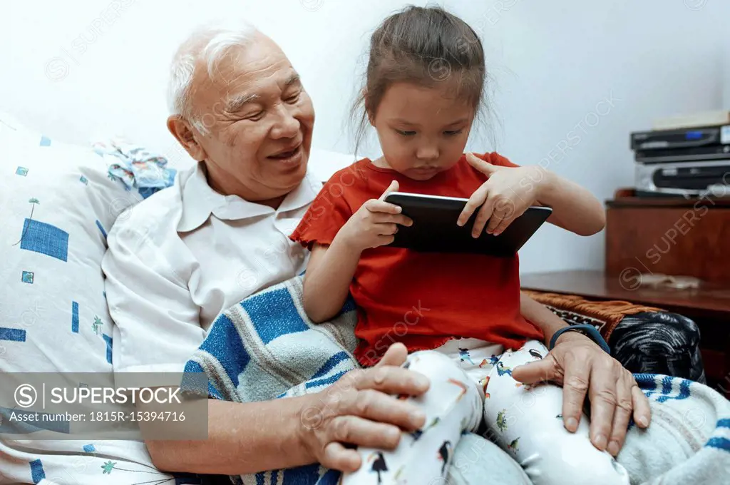 Grandfather and granddaughter with digital tablet at home