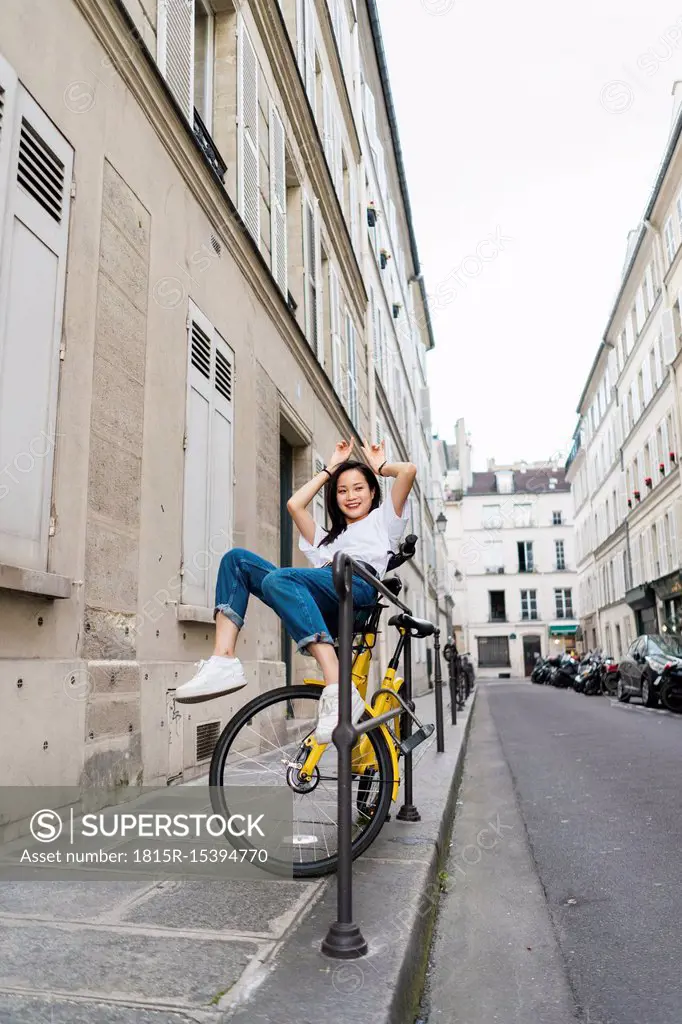 Playful young woman on bicycle at the roadside