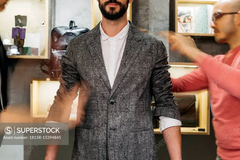 Two men working on new stylish look for handsome man in showroom