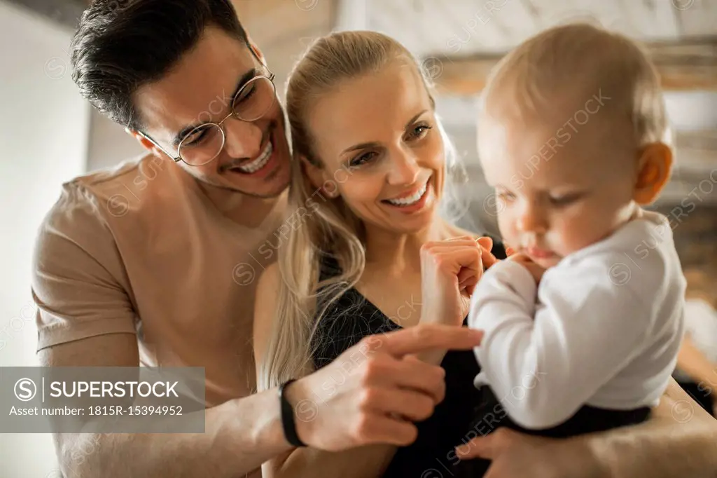 Happy young parents spending time at home with their baby girl