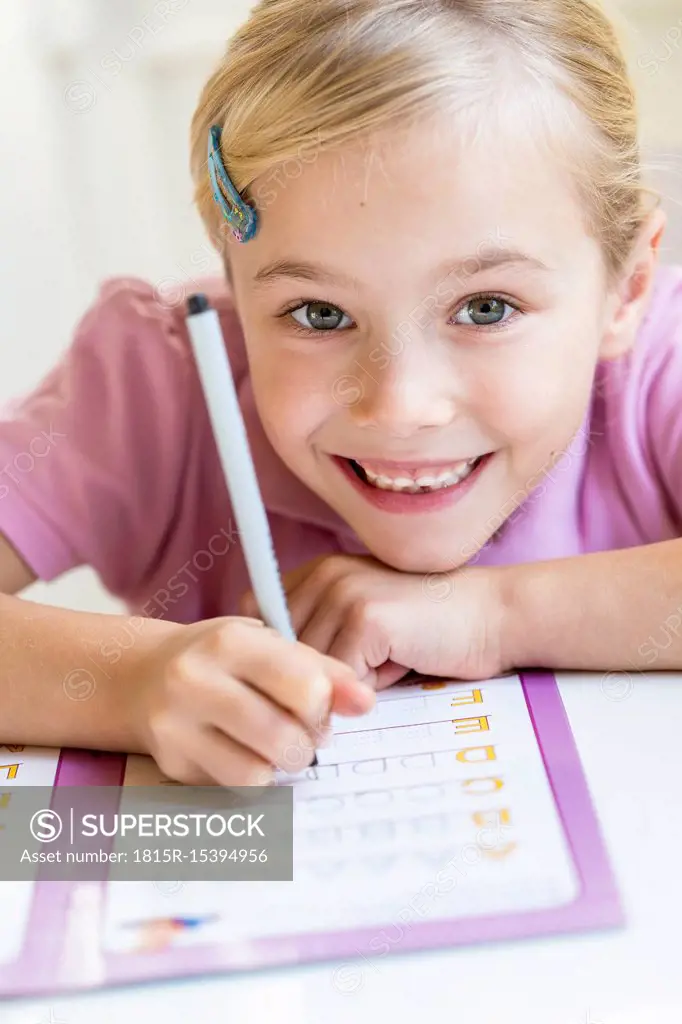 Portrait of smiling little girl writing alphabet