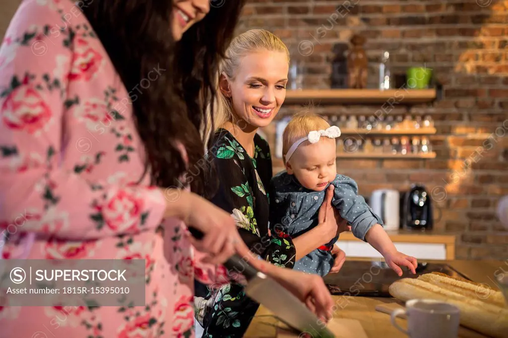 Female friends with baby girl preparing dinner together