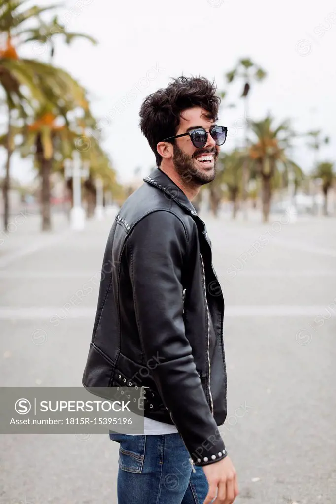 Spain, Barcelona, happy young man on promenade with palms