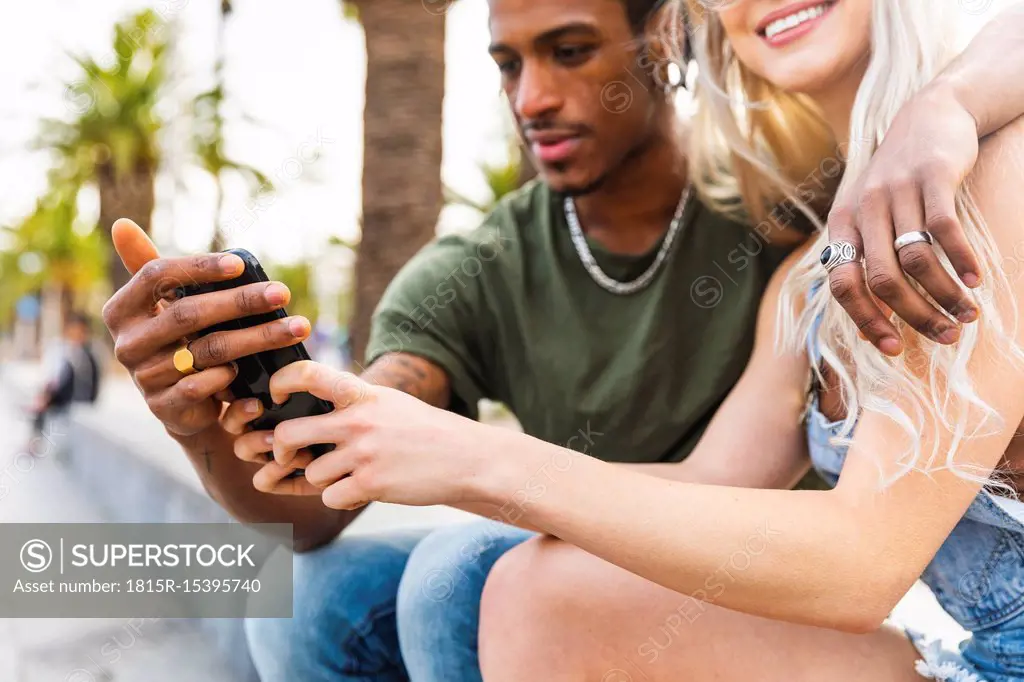 Hands of multicultural young couple holding smartphone