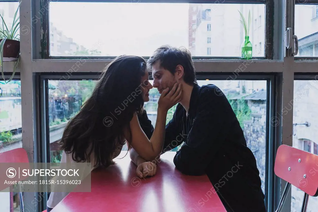 Young couple in love sitting at table at the window