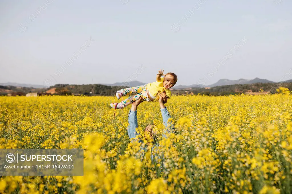 Spain, father and baby girl having fun together in a rape field