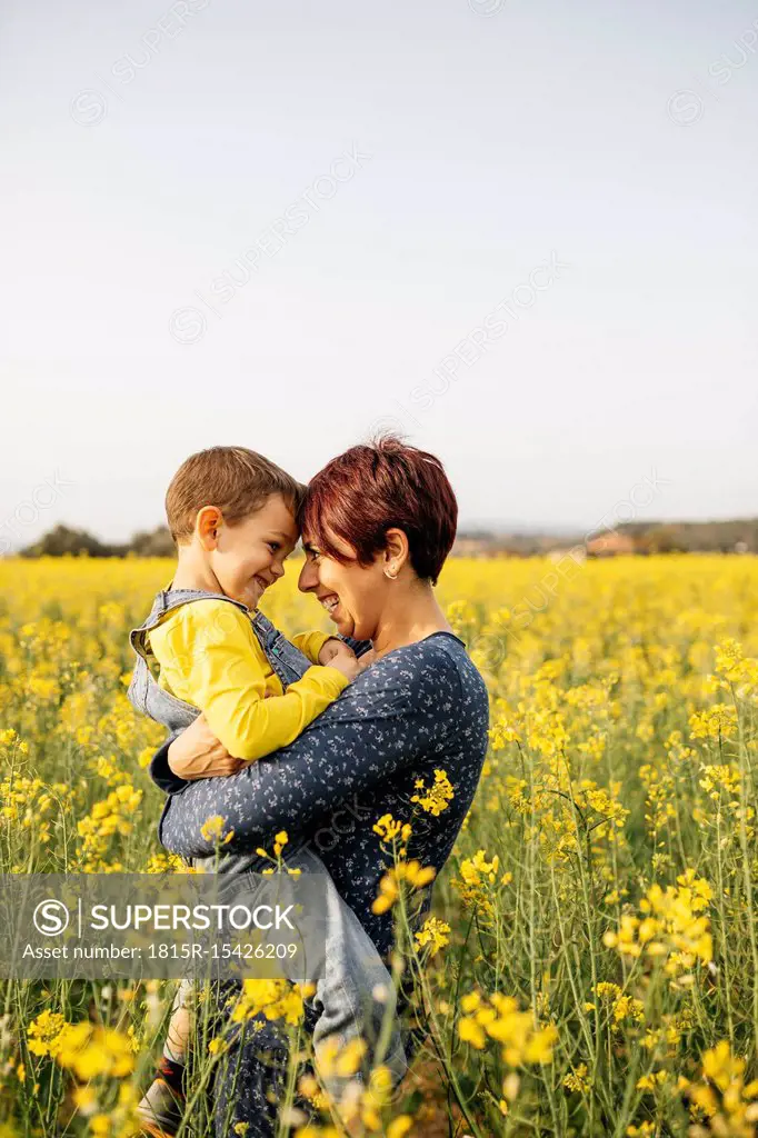 Mother standing with her little son in a rape field