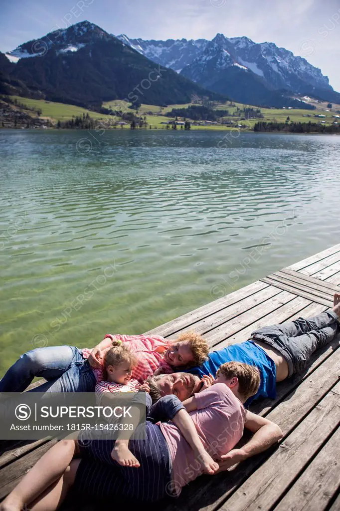 Austria, Tyrol, Walchsee, family lying on a jetty at the lakeside