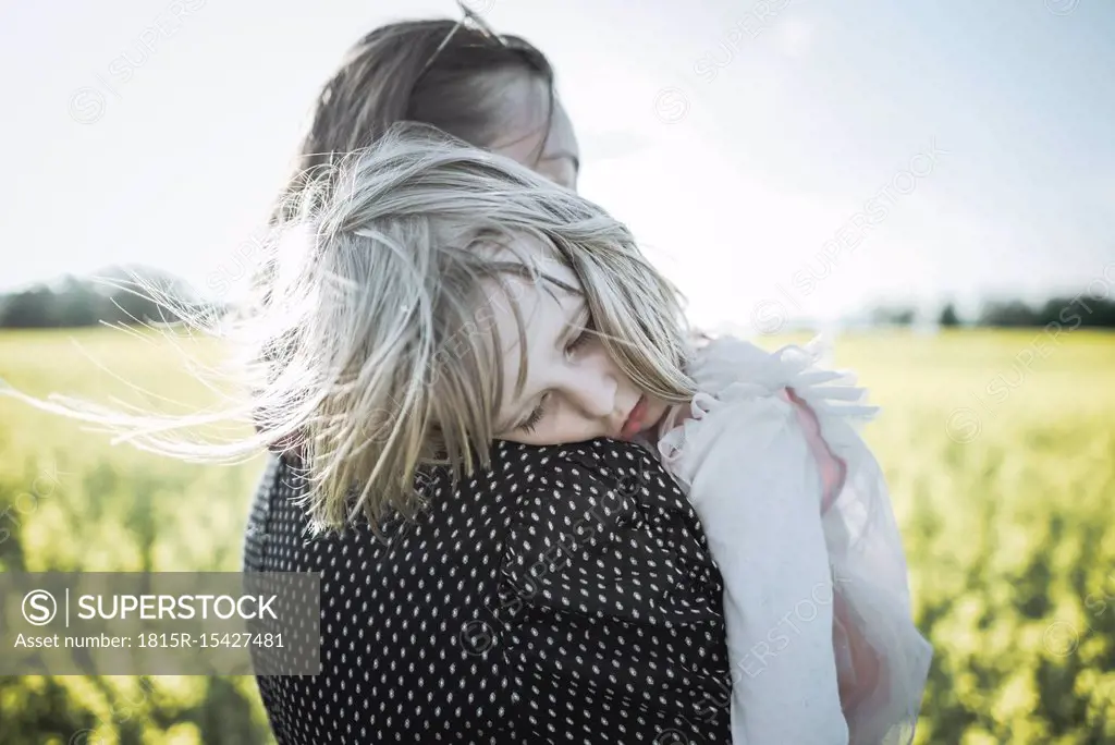 Portrait of little girl on her mother's arms in rape field