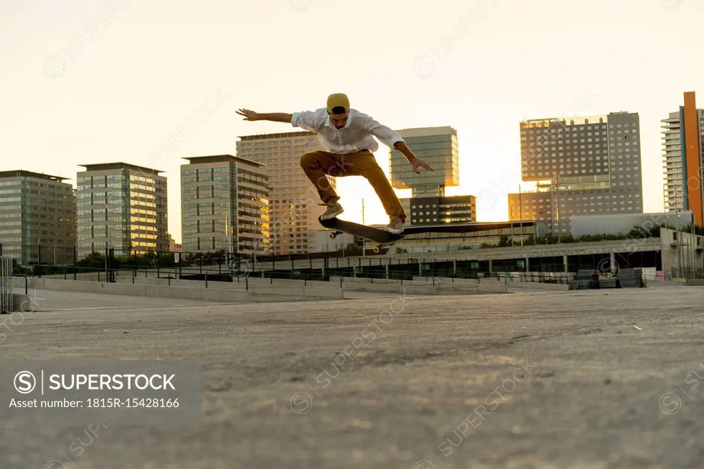 Young man doing a skateboard trick in the city at sunset