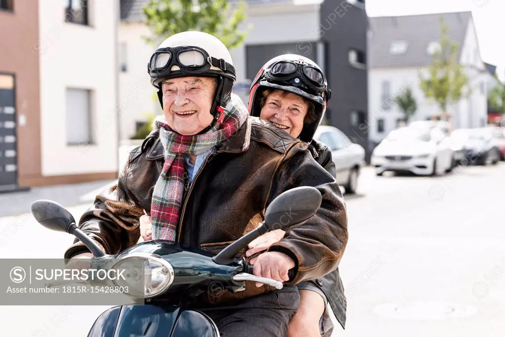 Happy senior couple riding motor scooter