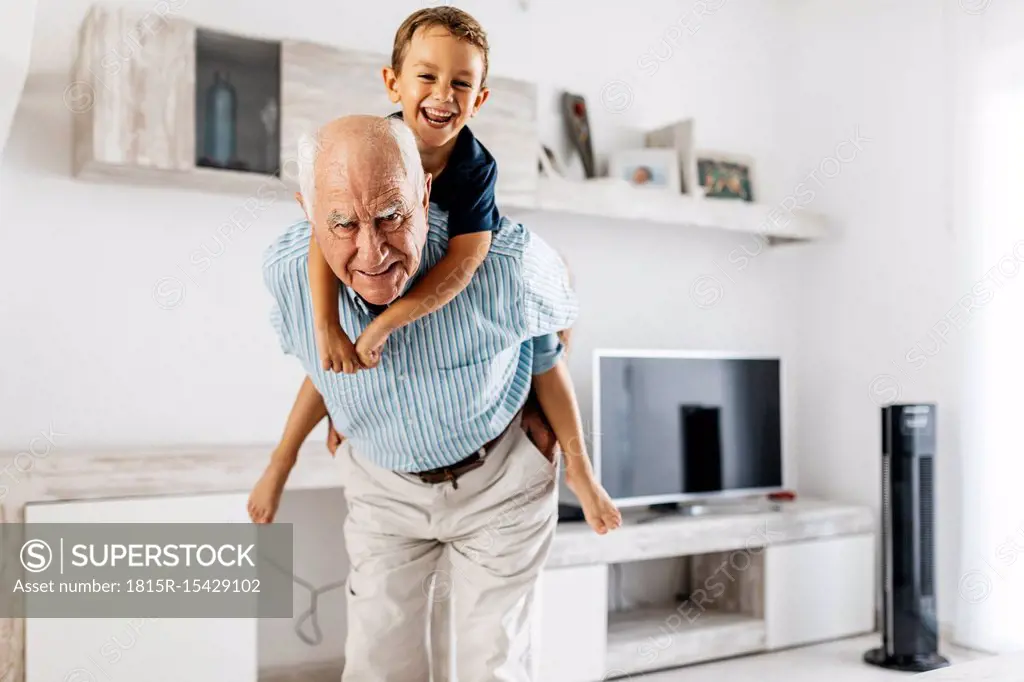 Portrait of grandfather giving his grandson a piggyback ride in the living room