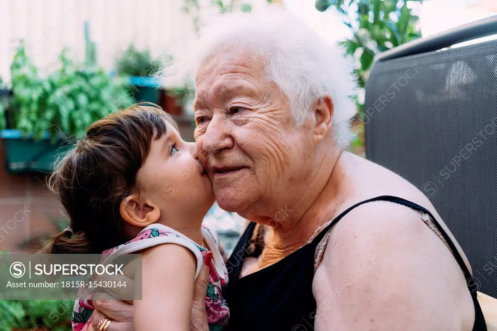 Baby girl kissing her grandmother on terrace