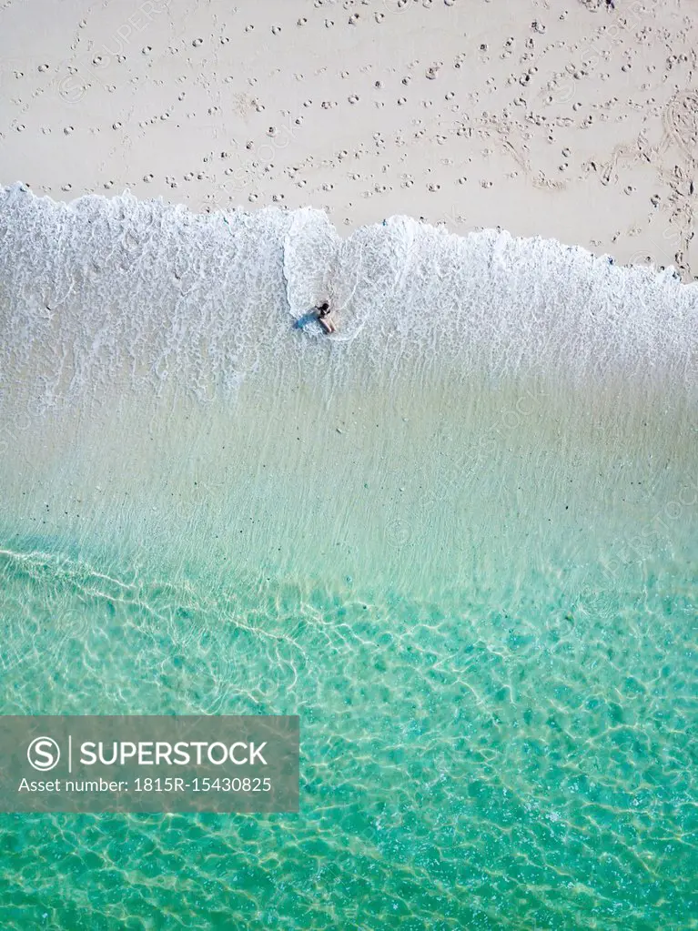 Indonesia, Bali, Young woman sitting on seashore