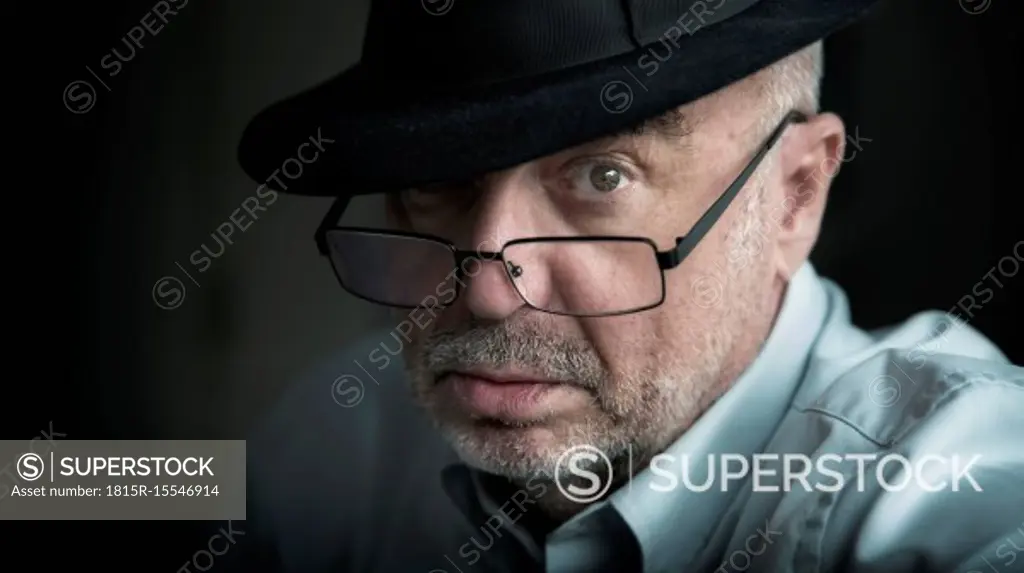 Portrait of serious looking senior man wearing glasses and hat