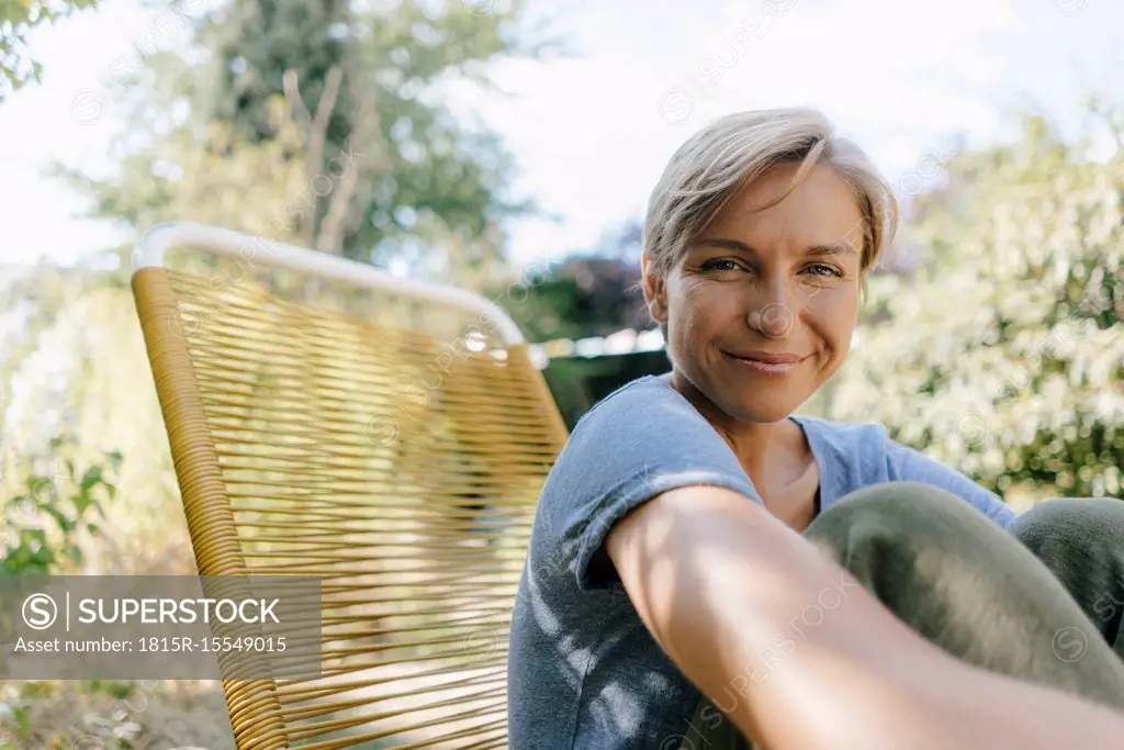 Portrait of smiling woman sitting in garden on chair