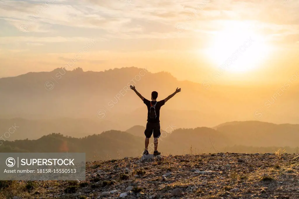 Spain, Barcelona, Natural Park of Sant Llorenc, man hiking and cheering at sunset