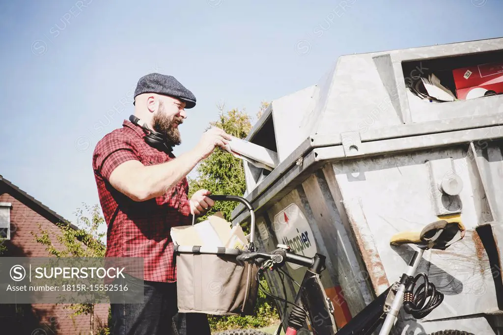 Cyclist recycling waste paper in paper bank