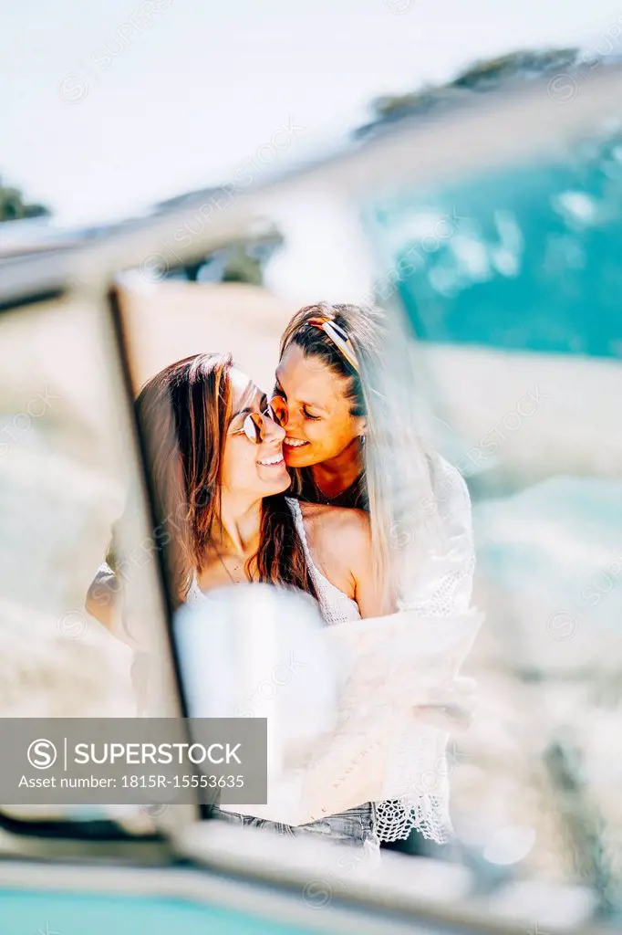 Lesbian couple doing a road trip, kissing and embracing in nature