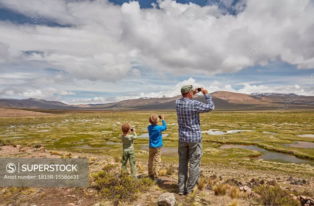 Peru, Chivay, Colca Canyon, father and sons taking pictures of swamp landscape in the Andes