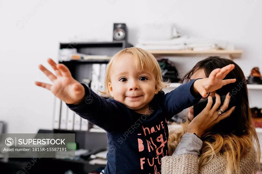 Portrait of a girl with mother at desk talking on cell phone