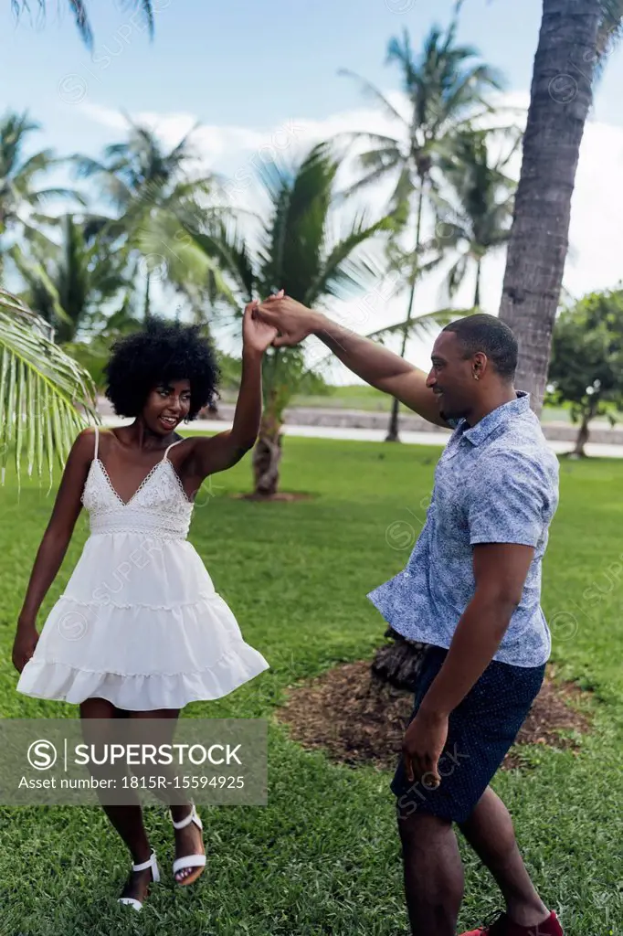 USA, Florida, Miami Beach, happy young couple dancing in a park in summer