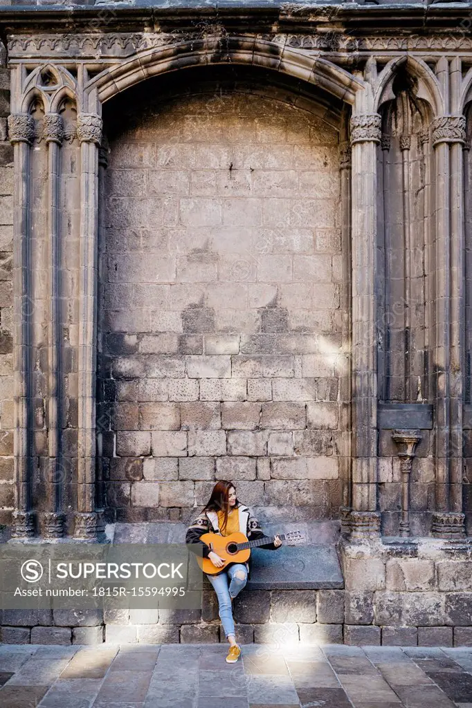 Red-haired woman playing the guitar in the city