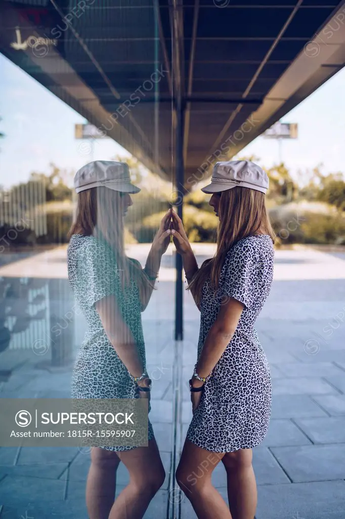 Attractive young woman in leopard print dress reflected in windowpane