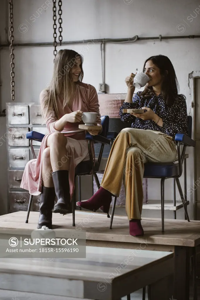 Two friends drinking tea together in a loft