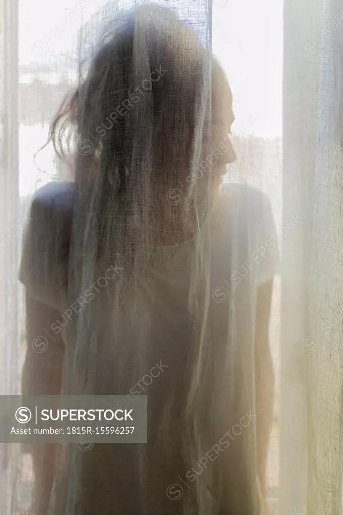 Silhouette of a young woman behind a curtain