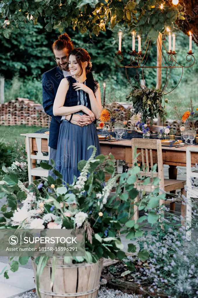 Happy bride and groom embracing at festive laid table outdoors